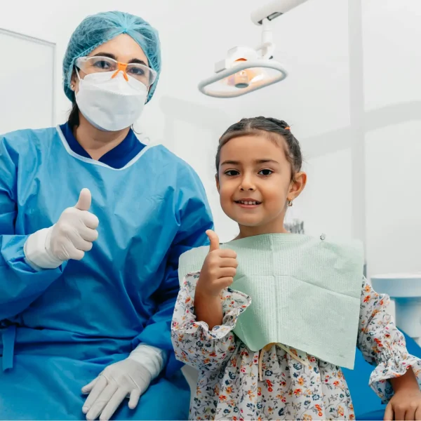 Dentist in scrubs and mask with happy young patient giving thumbs up after a great visit at ZPD Dental Clinic