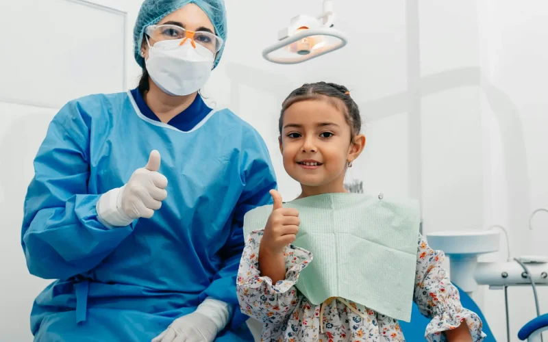 Dentist in scrubs and mask with happy young patient giving thumbs up after a great visit at ZPD Dental Clinic