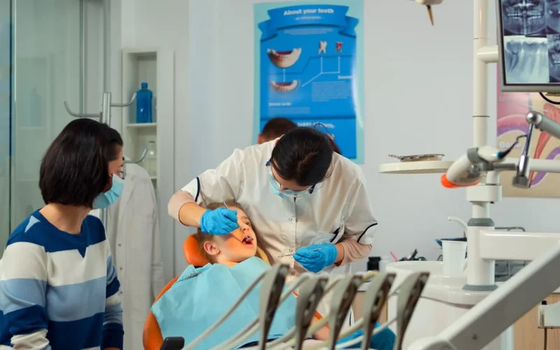 Female dentist treating a young boy’s teeth while his mother watches at ZPD: Zionsville Pediatric Dentistry