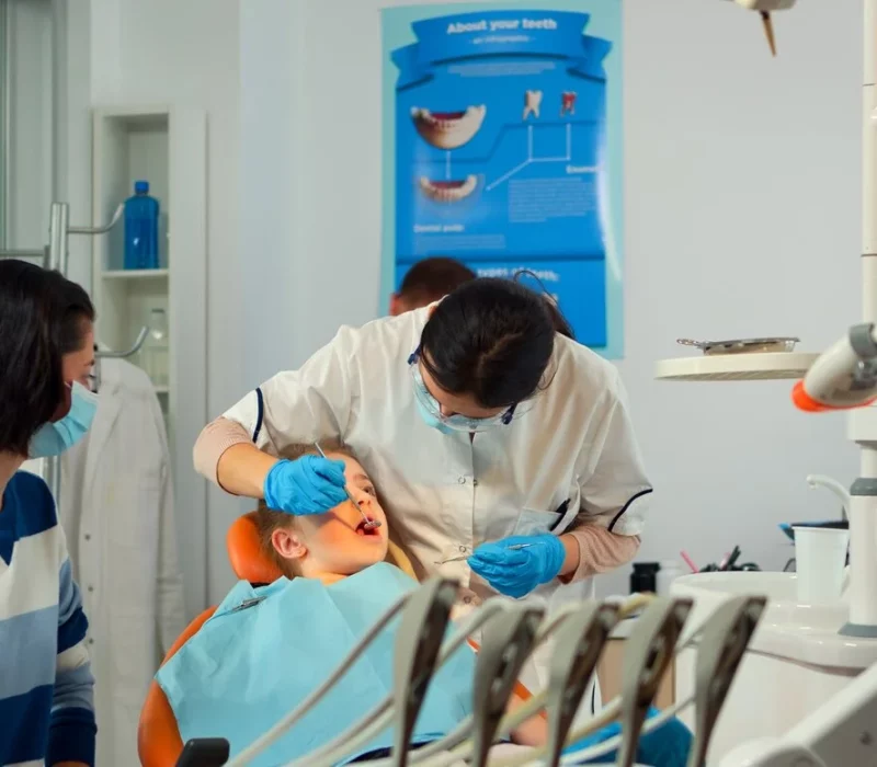 Female dentist treating a young boy’s teeth while his mother watches at ZPD: Zionsville Pediatric Dentistry