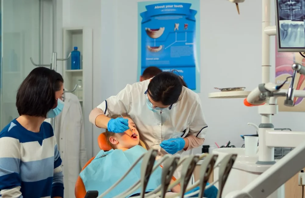 Female dentist treating a young boy’s teeth while his mother watches at ZPD: Zionsville Pediatric Dentistry