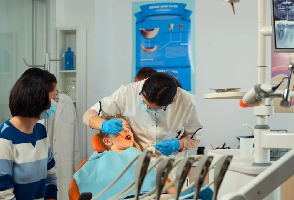 Female dentist treating a young boy’s teeth while his mother watches at ZPD: Zionsville Pediatric Dentistry
